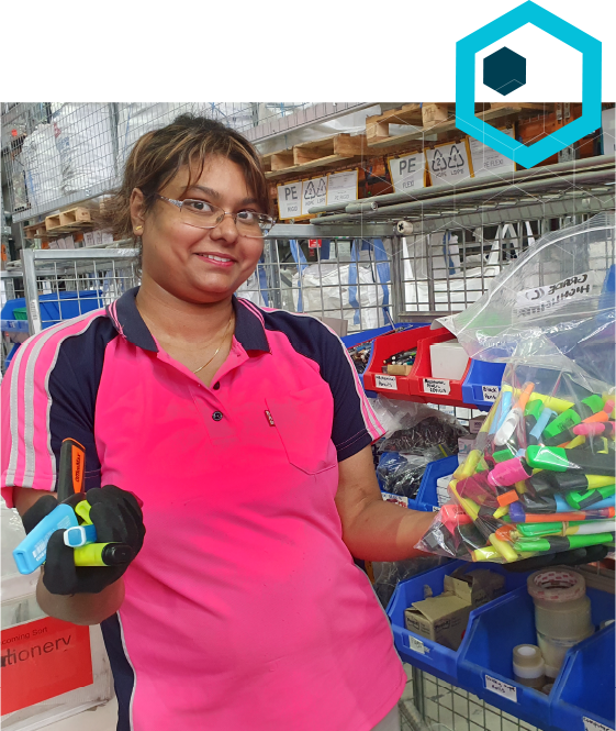 Tight crop of a woman in bright pink polo shirt collects stationary in a plastic bag in a warehouse
