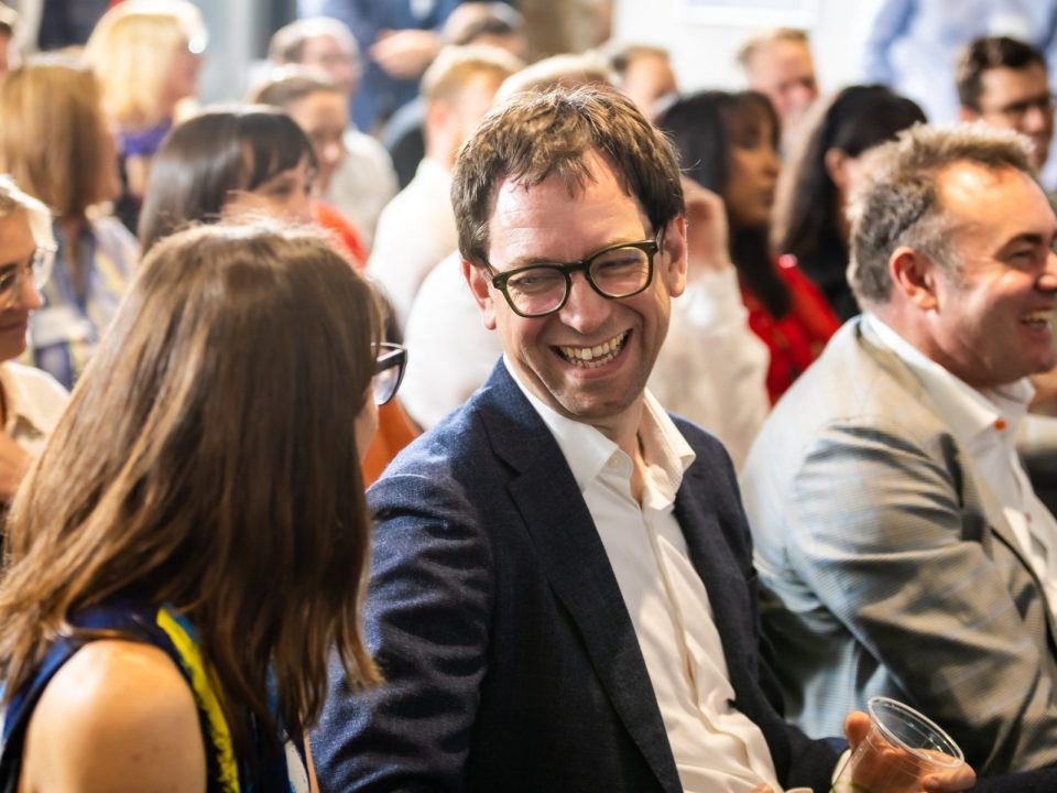 Luke Terry sitting at an event and smiling at a woman next to him