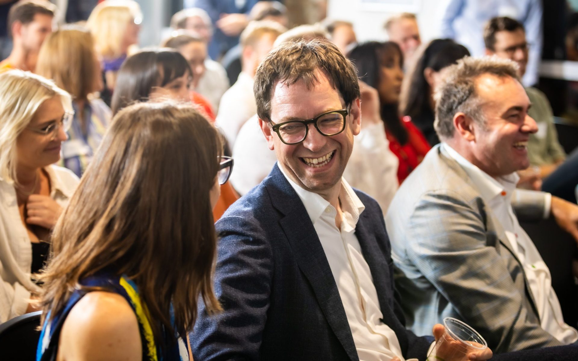 Luke Terry sitting at an event and smiling at a woman next to him