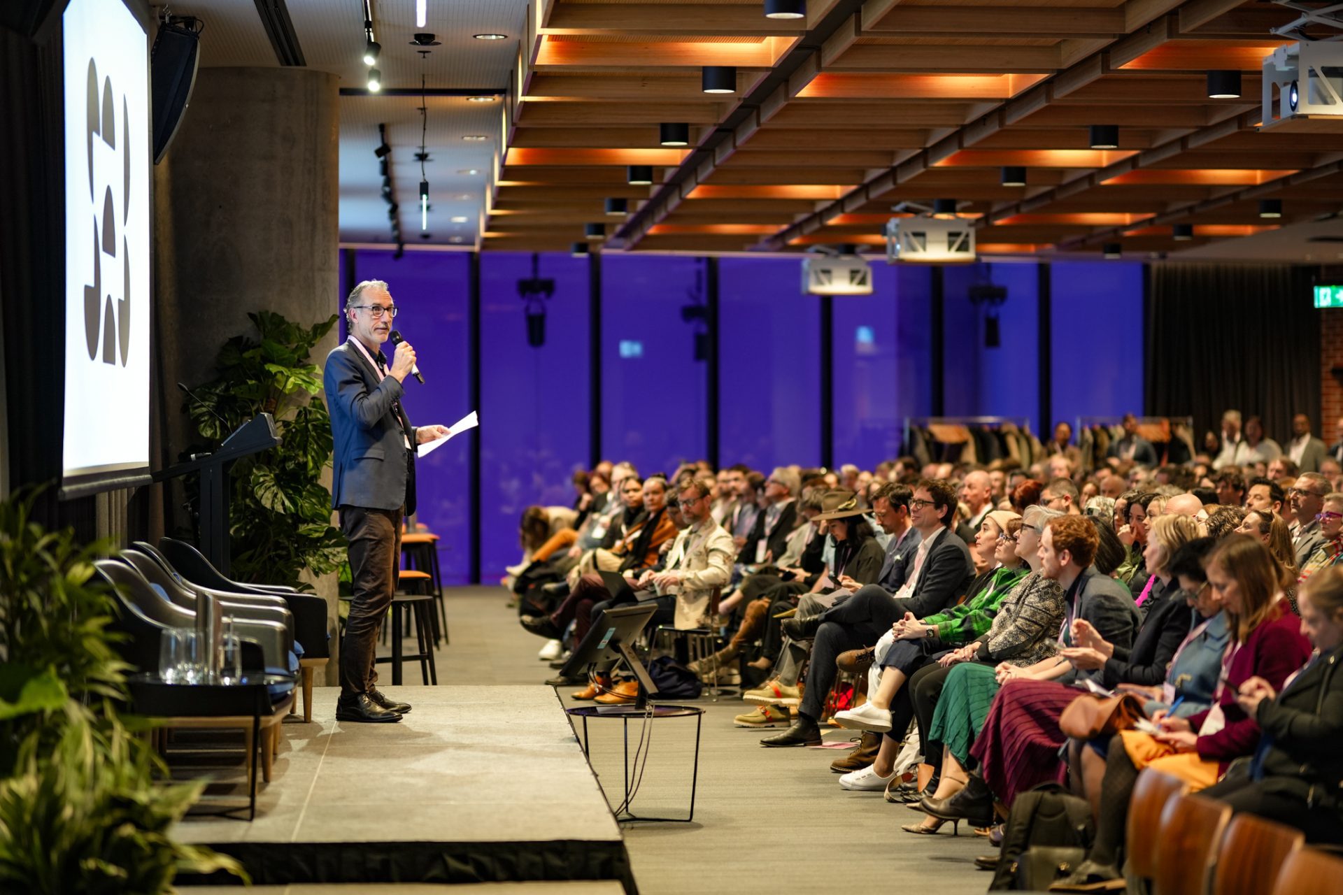 A group of people from social enterprises listen attentively to a speaker on stage