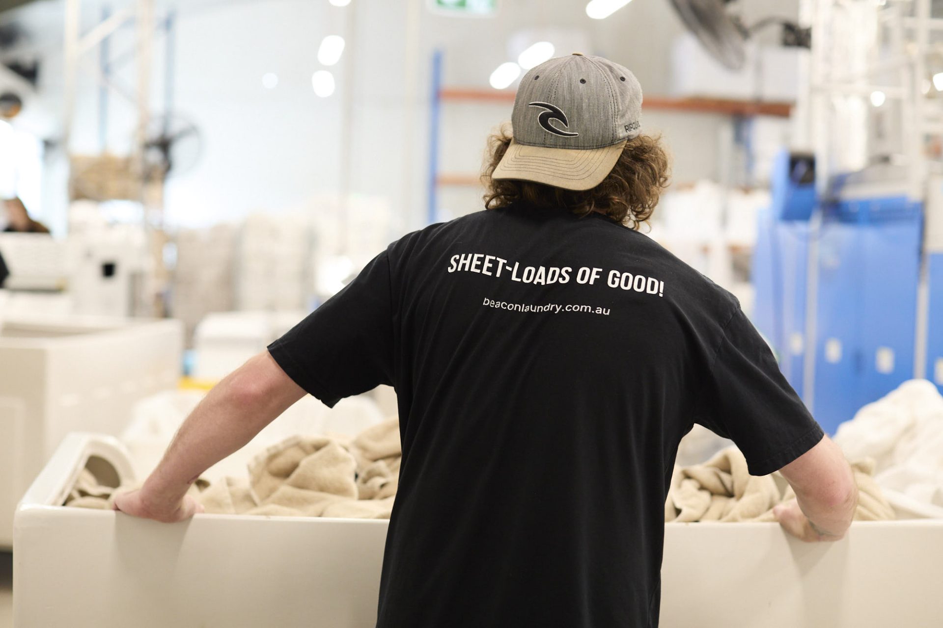 Beacon Laundry employee pushing a tub of sheets in the laundry.
