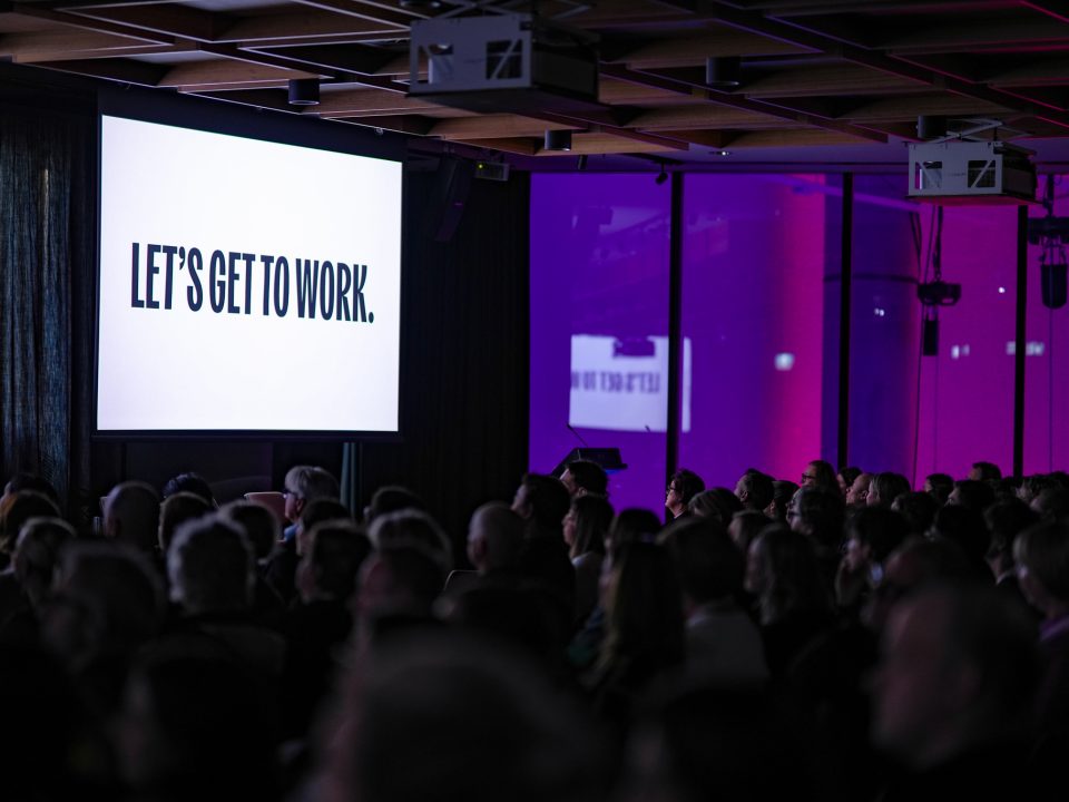 Social Enterprise Jobs Summit opening session - large conference room with a screen that says 'lets get to work'