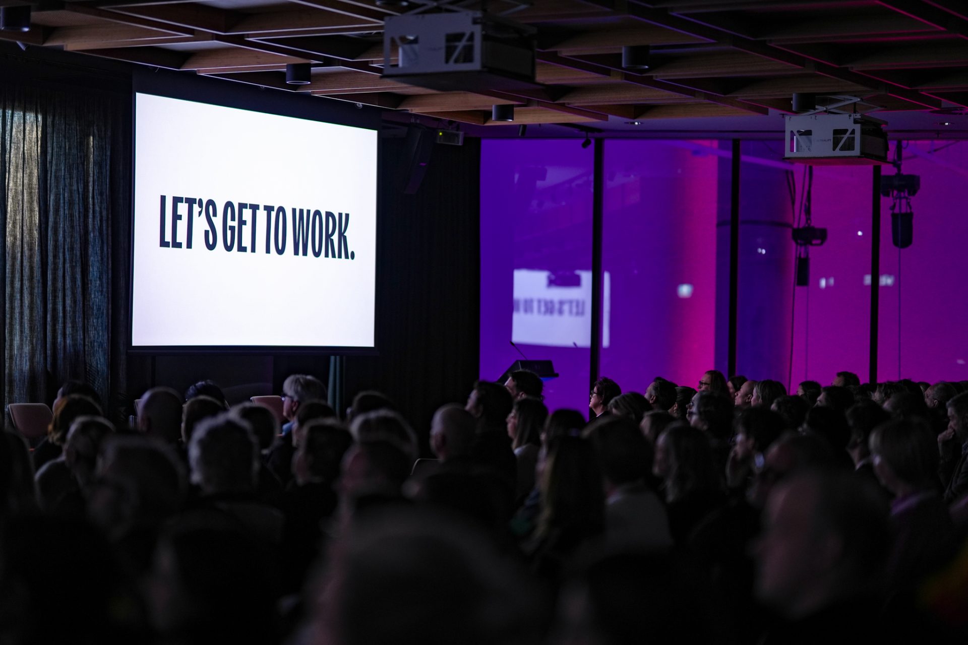 Social Enterprise Jobs Summit opening session - large conference room with a screen that says 'lets get to work'